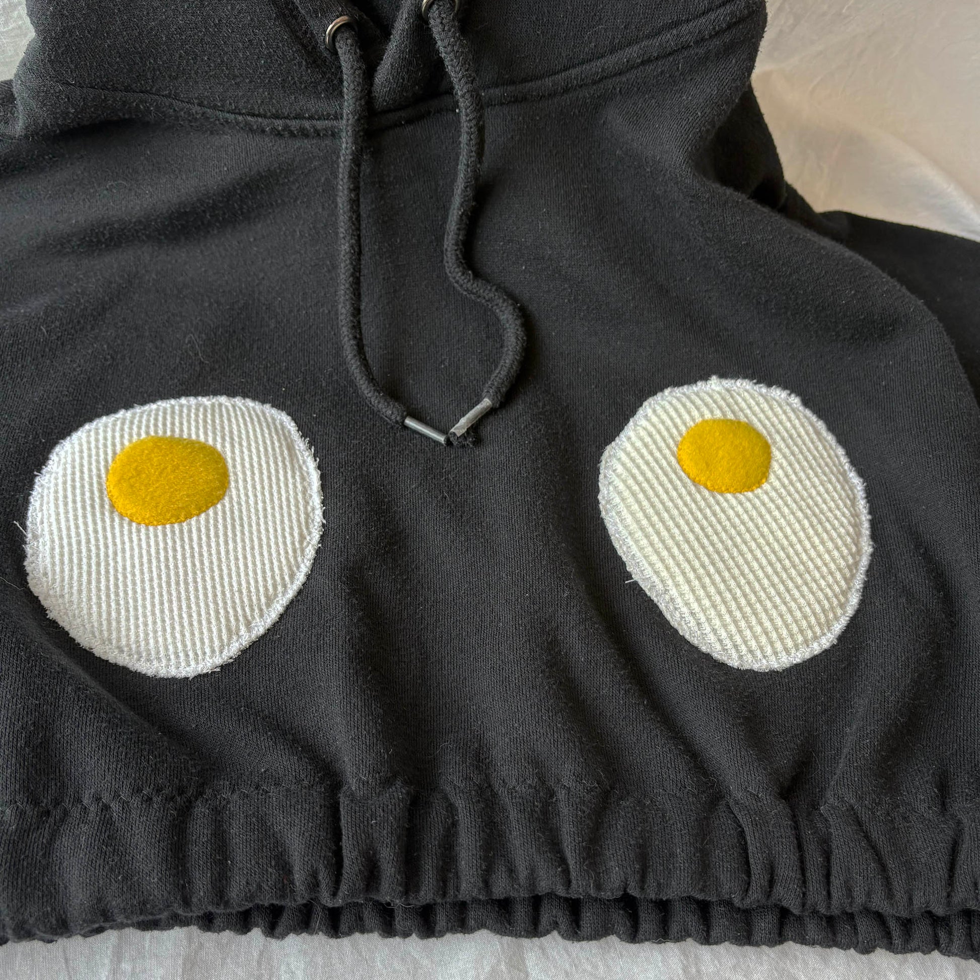 Black hoodie with knitted eggs design on a light background
