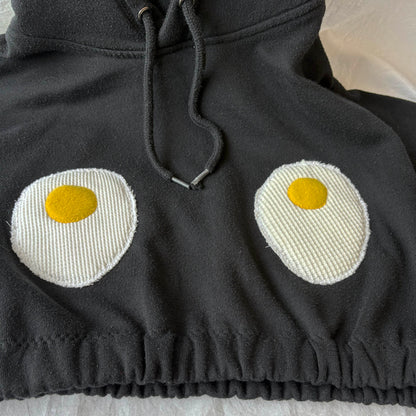 Black hoodie with knitted eggs design on a light background