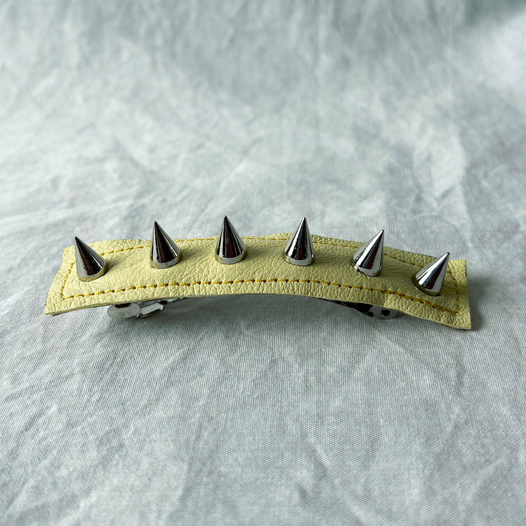 Hair clip with metal spikes on a textured gray background