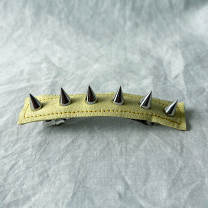 Hair clip with metal spikes on a textured gray background