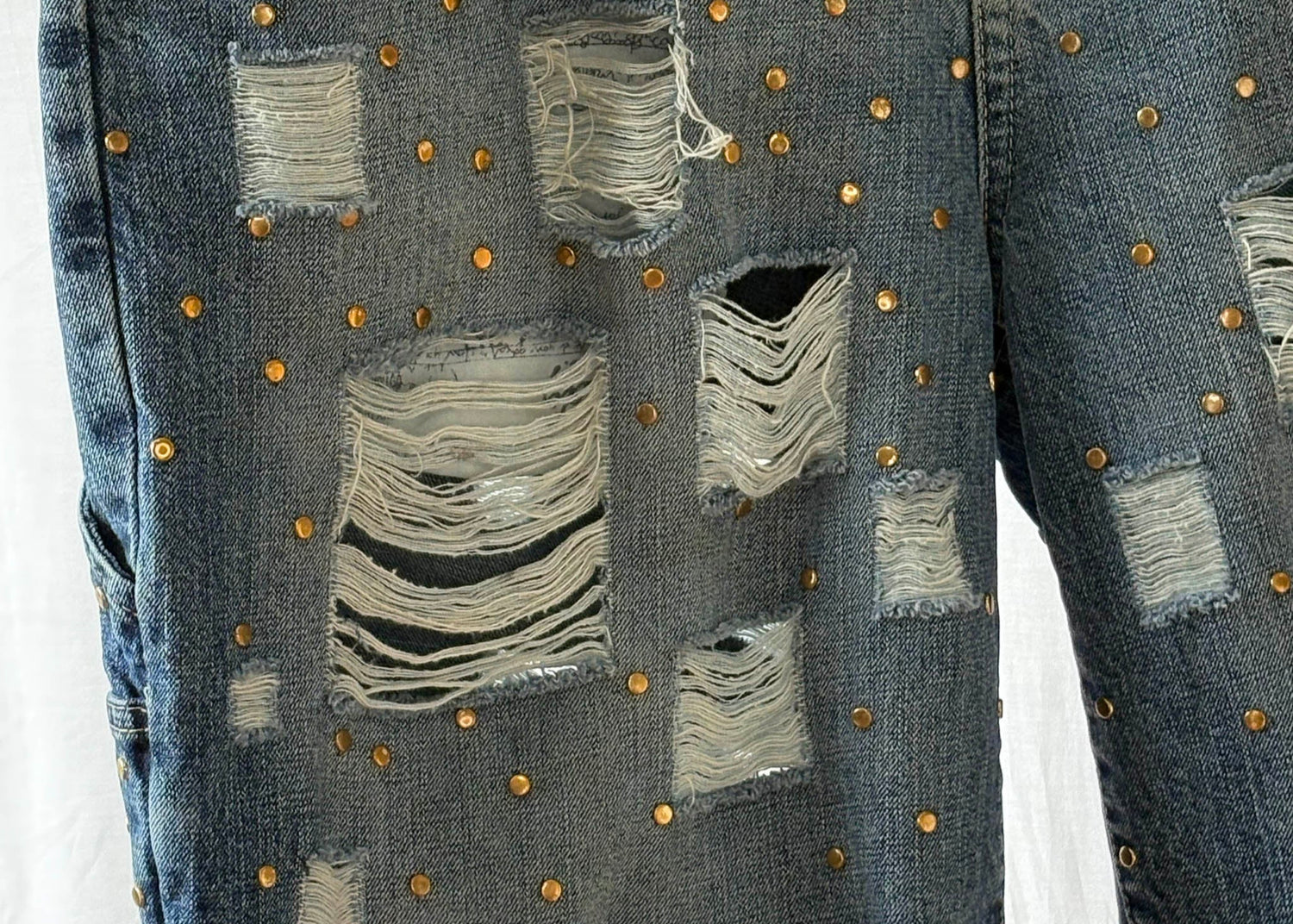 Close up of window pane distressed denim with gold studs.