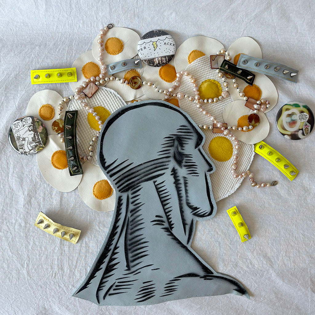 Artistic arrangement of products, a bust and various small objects on a textured white surface